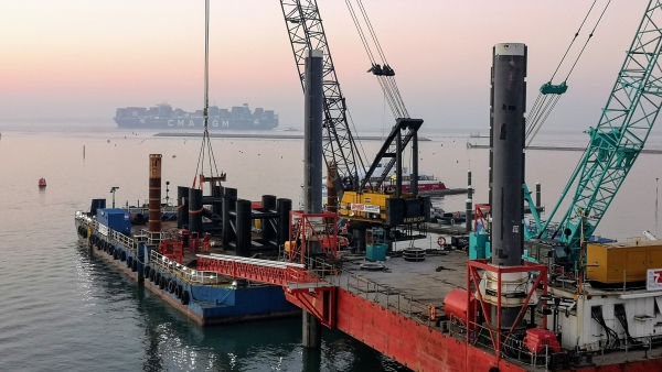 The White Shipyard in East Cowes with a container ship near the horizon line.